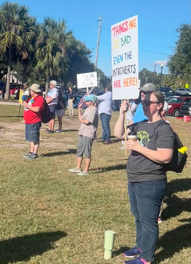 Protestor holding sign that reads "Things are so bad even the introverts are here!"